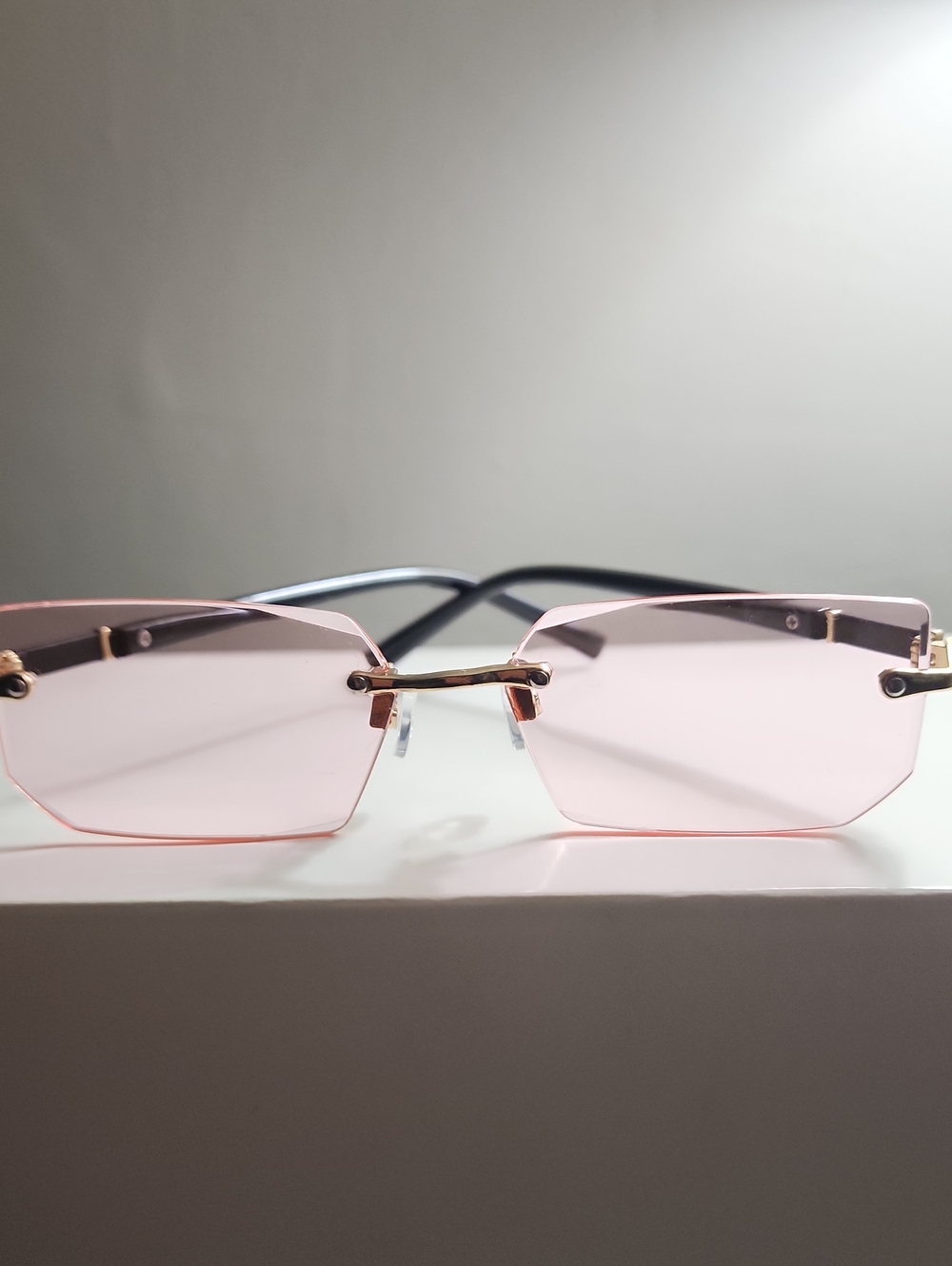 Rimless Pink Lens Sunglasses with Gold Accents and Black Temples